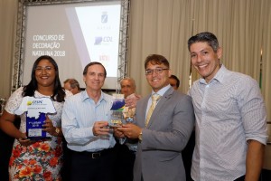 O presidente Romildo Barbosa da Silva Júnior e a executiva Ingrid da Silva de Assis recebendo o troféu das mãos do presidente da FCDL/RN, Afrânio Miranda.